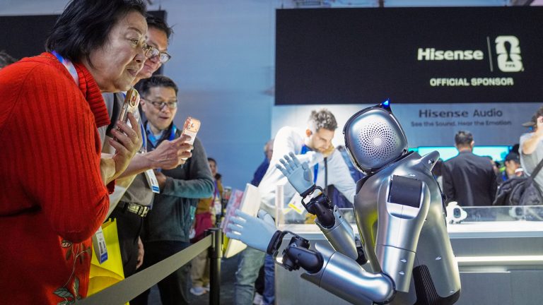 Attendees take photos of the UniTree autonomous robot which is posing with its boxing gloves and headgear