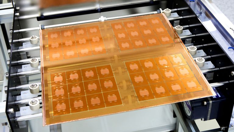 close up on a grid of glass substrate test units held by a gloved hand